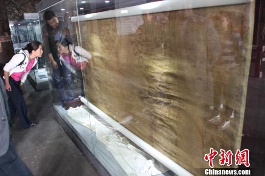     图为由捻金线织成的陀罗尼经被，经被约三米见方，明黄缎底，被面上织有众多佛经、佛像、佛塔、花纹等装饰，既有佛教的神圣，又不失皇室的威严。　白云水　摄