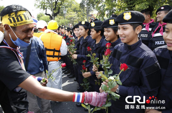2013年12月03日，曼谷总理府与曼谷警署允许反政府示威民众进入，双方进入暂时&ldquo;停战&rdquo;状态迎接泰王生日。曼谷警察总署，女警们手持鲜花送给反政府示威民众。图片来源：Manish Swarup/东方IC 